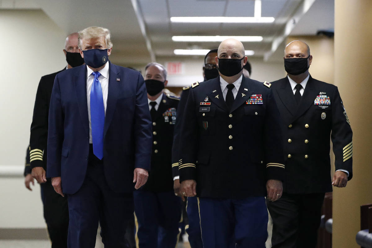 FILE - In this July 11, 2020, file photo President Donald Trump, foreground left, wears a face ...