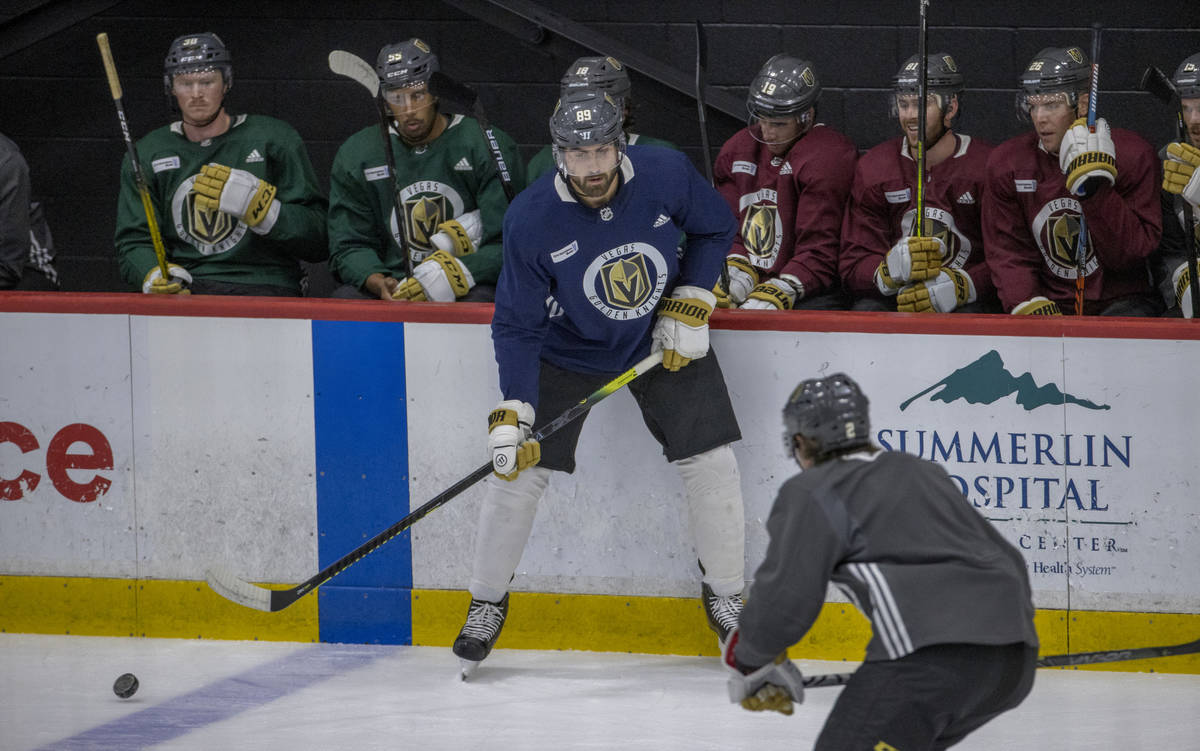 Vegas Golden Knights right wing Alex Tuch (89, left) eyes the puck as defenseman Zach Whiteclou ...