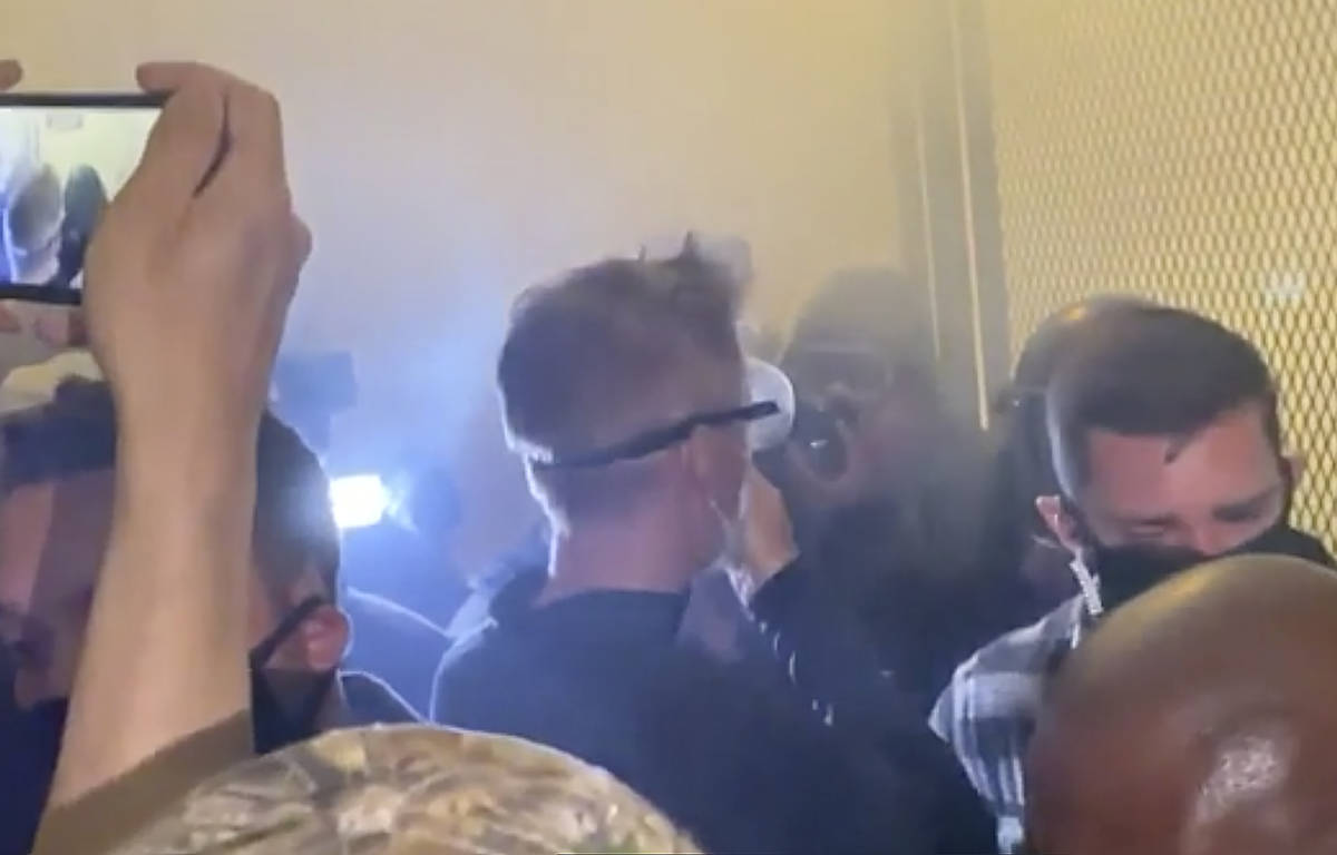 In this image made from video released by Jonathan Maus, Portland Mayor Ted Wheeler, center in ...