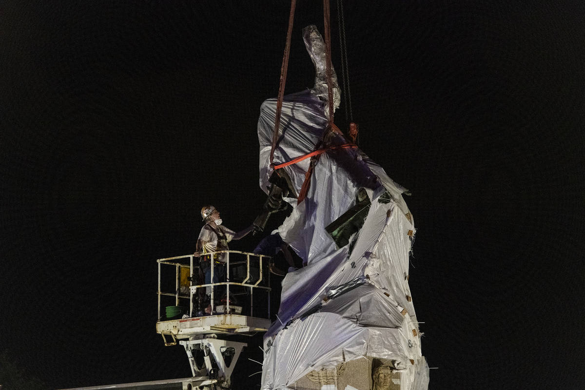 City crews inspect the straps that are around the Christopher Columbus statue in Grant Park as ...