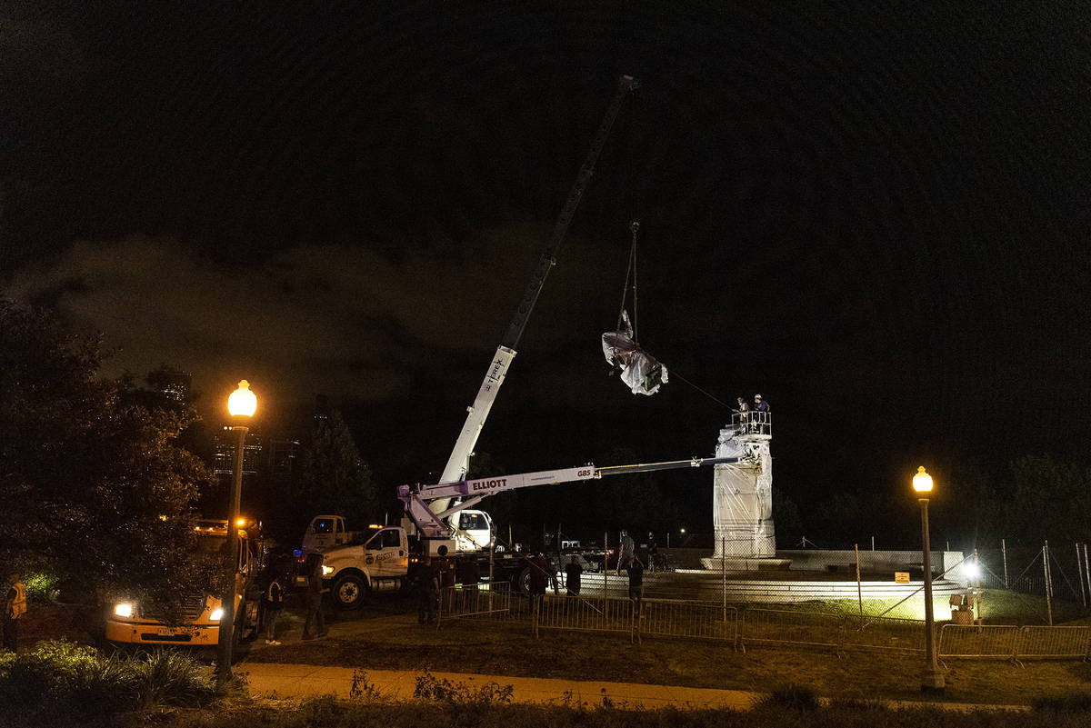 A crane removes the Christopher Columbus statue in Grant Park from its plinth, Friday, July 24, ...
