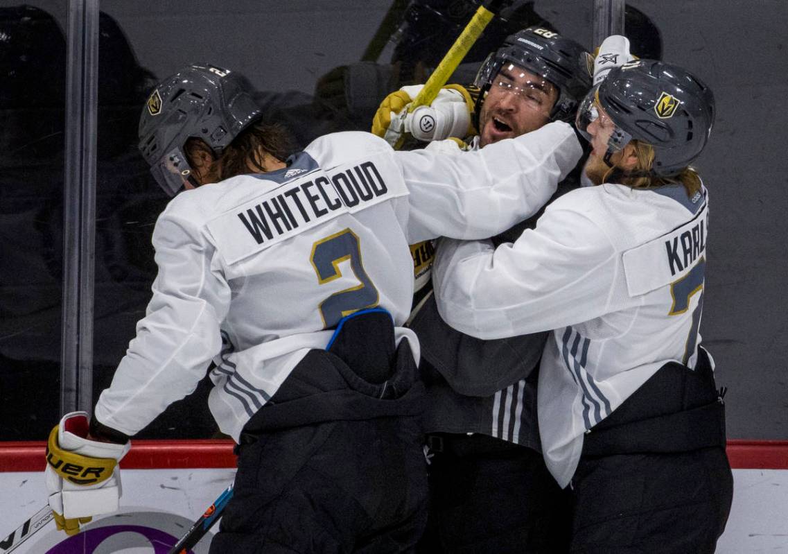 Vegas Golden Knights left wing William Carrier (28, center) is wrapped up by defenseman Zach Wh ...