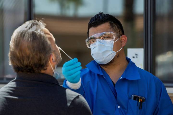 Practice Manager Jose Tirana conducts a COVID-19 test on a patient at Sahara West Urgent Care & ...