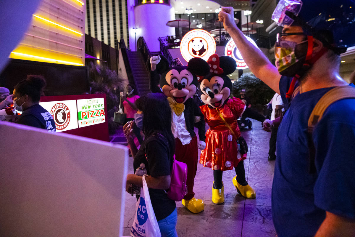 Street performers look as Black Lives Matter protesters walk on the Las Vegas Strip on Saturday ...