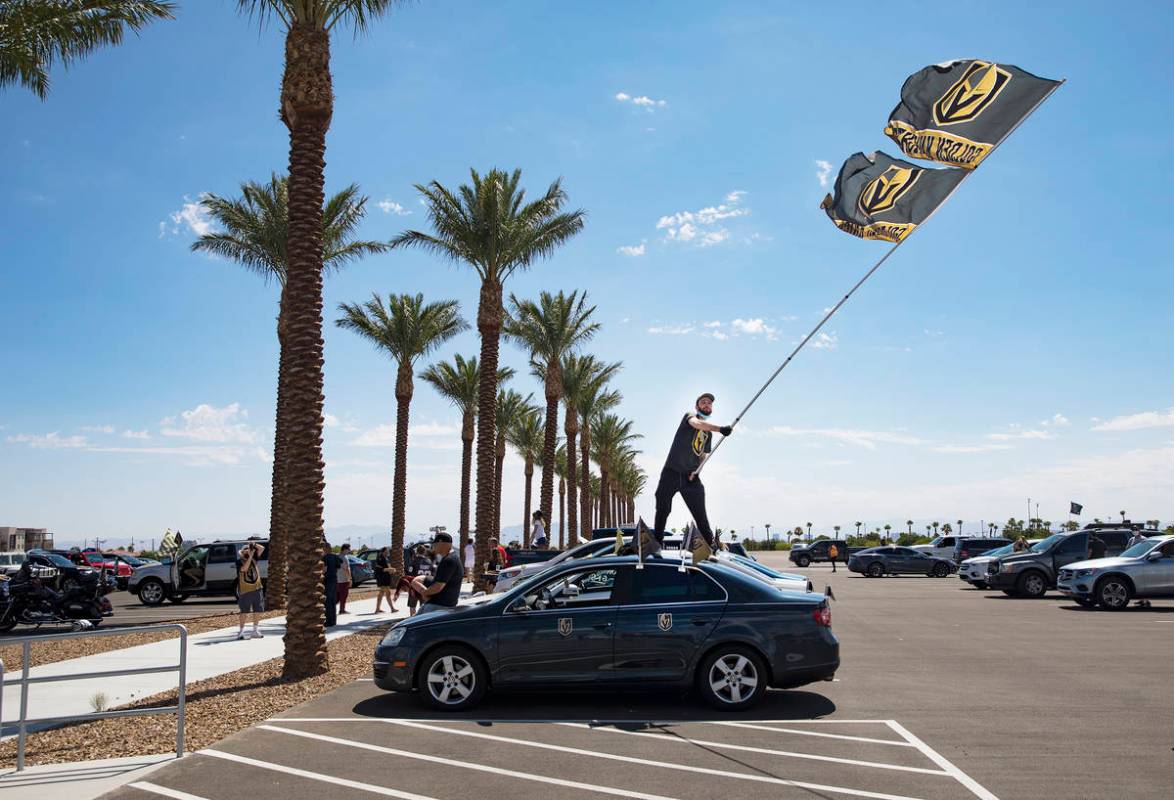 Matt Helfst waves a flag as he waits for the Golden Knights players to pass in buses as they le ...