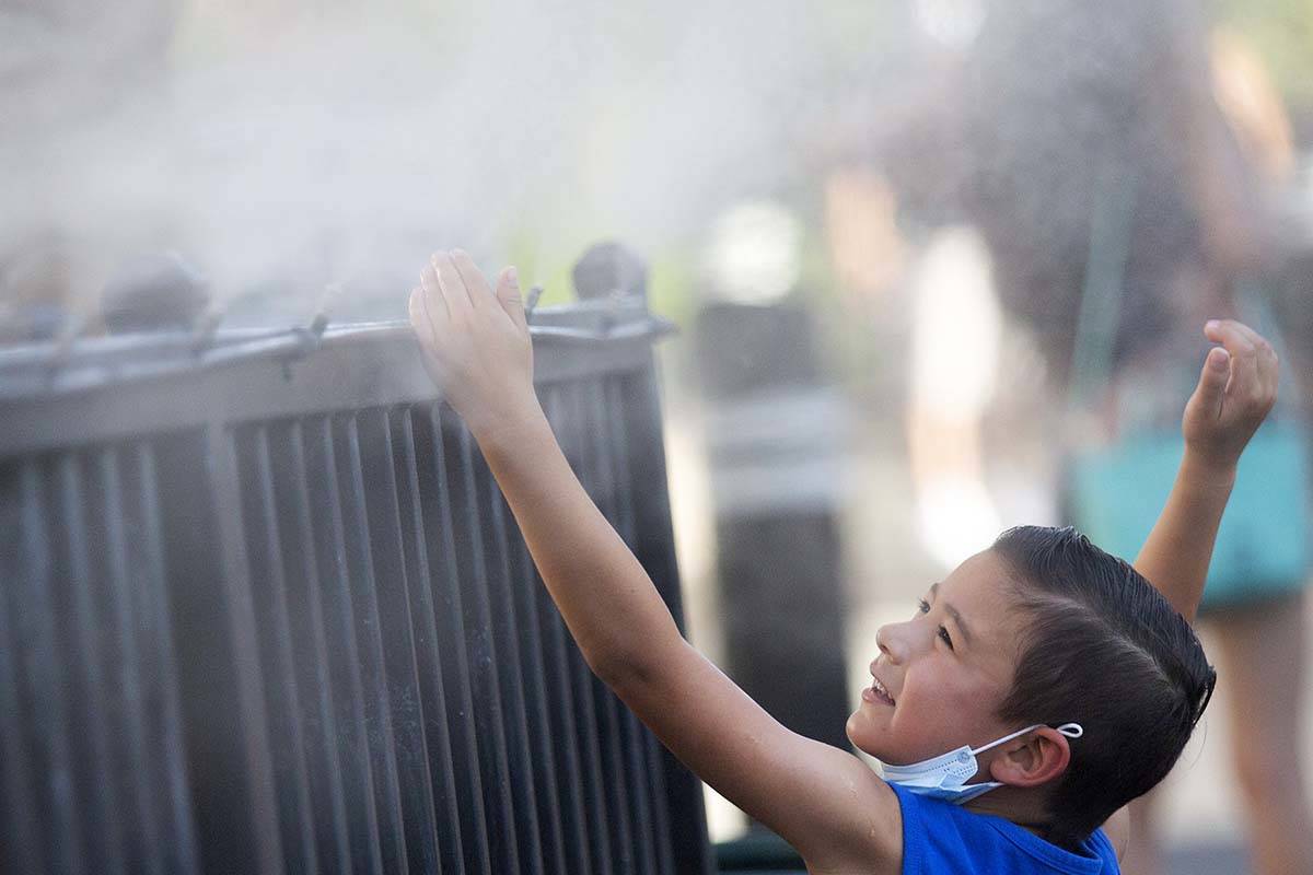 Brody Lester, 5, of California, cools off with the mist outside Hexx Bar and Grill's patio on t ...
