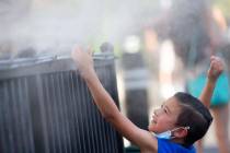 Brody Lester, 5, of California, cools off with the mist outside Hexx Bar and Grill's patio on t ...