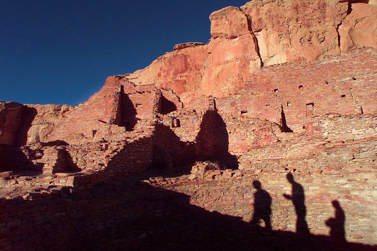 Tourists cast their shadows on the ancient Anasazi ruins of Chaco Culture National Historical P ...