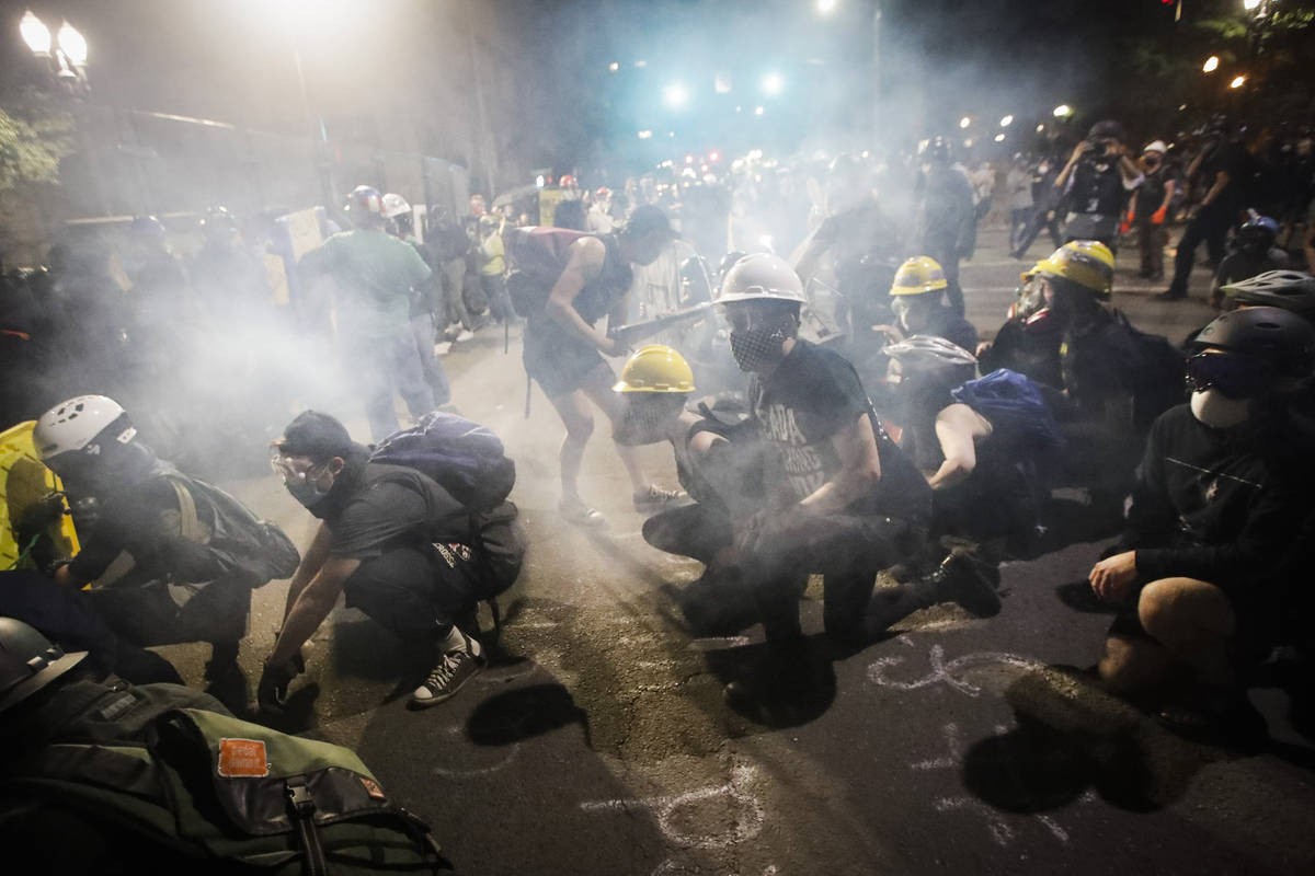 Demonstrators sit and kneel as tear gas fills the air during a Black Lives Matter protest at th ...