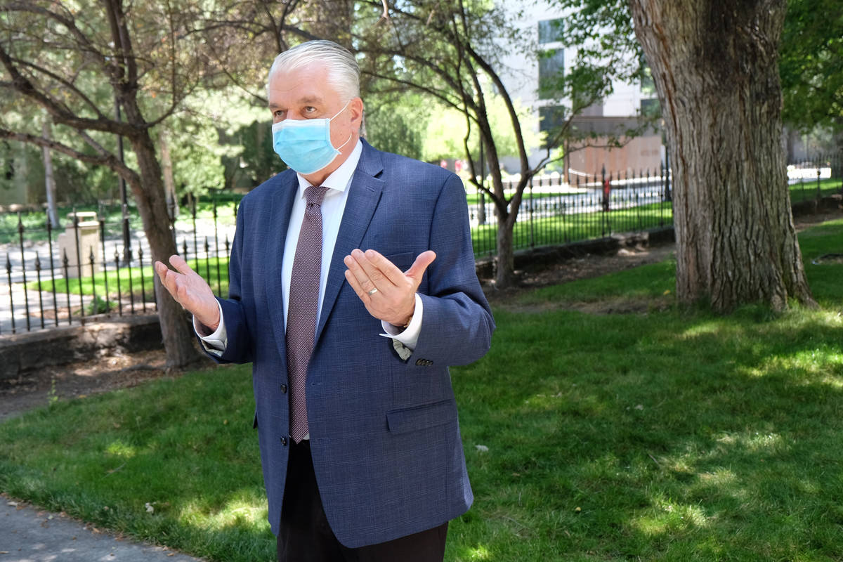 A masked Gov. Steve Sisolak speaks to reporters outside the Capitol during the Nevada Legislatu ...