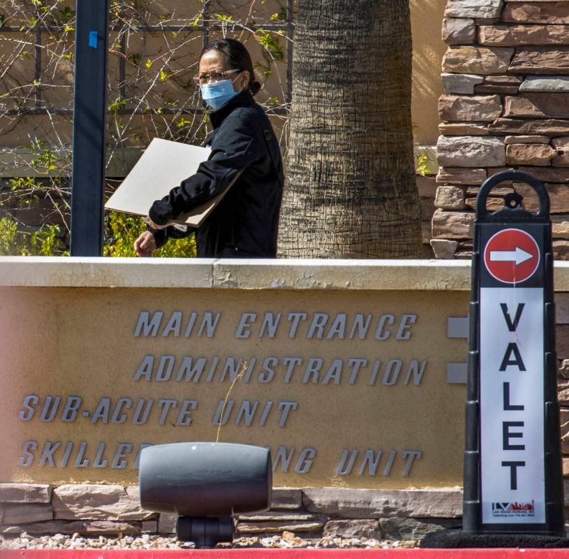 A woman walks outside of The Heights of Summerlin, where there have been numerous deaths due to ...