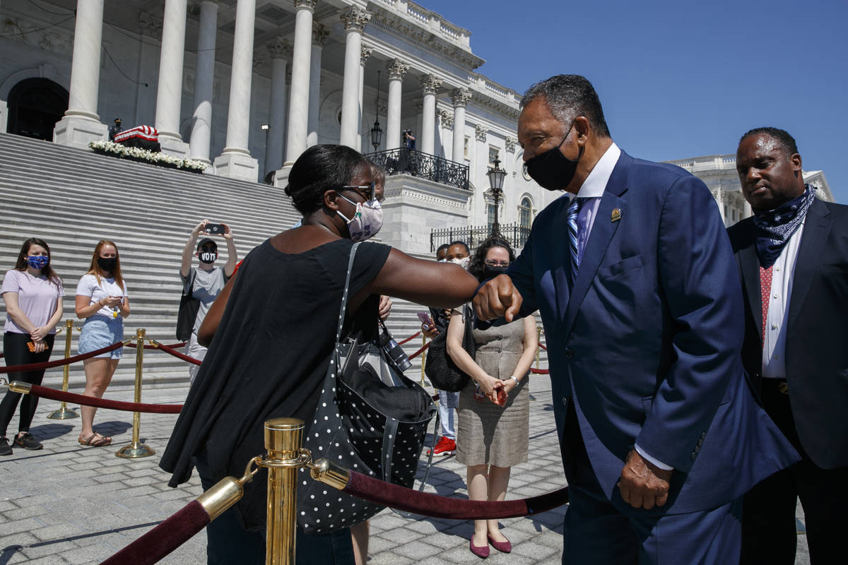 Tonya Jones, of New York City, left, bumps elbows with the Rev. Jesse Jackson, as he leaves aft ...