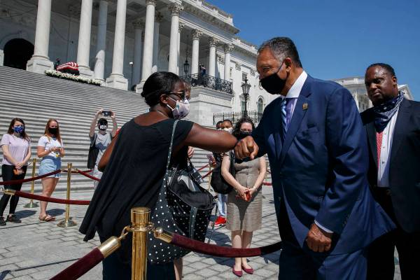 Tonya Jones, of New York City, left, bumps elbows with the Rev. Jesse Jackson, as he leaves aft ...