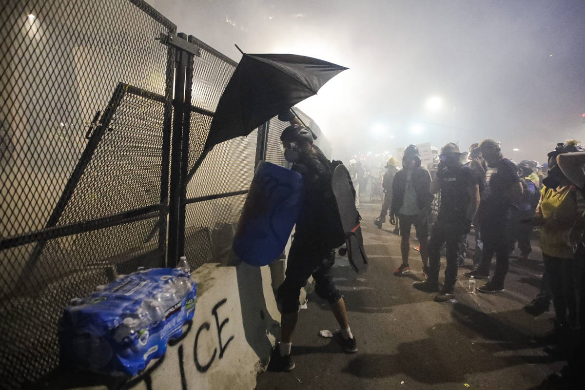 Demonstrators are tear-gassed by federal officers during a Black Lives Matter protest at the Ma ...
