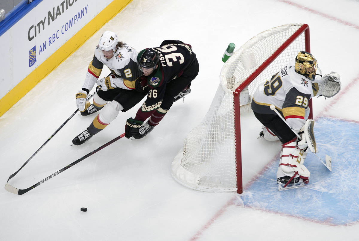 Arizona Coyotes' Christian Fischer (36) and Zach Whitecloud (2) battle for the puck as Vegas Go ...