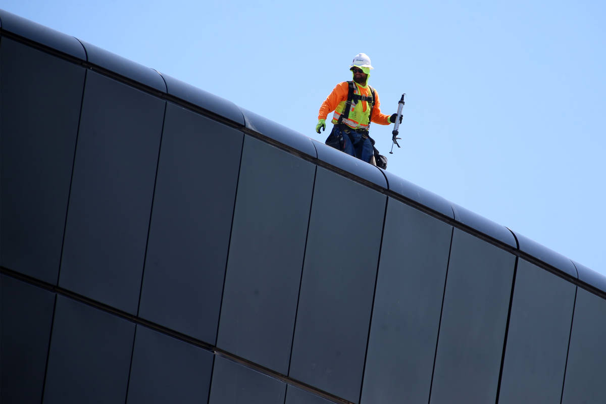 A worker stands of the roof of the Raiders Allegiant Stadium in Las Vegas, Tuesday, April 21, 2 ...
