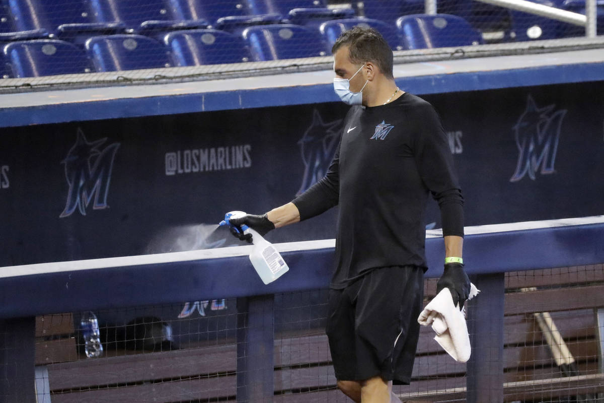 FILE - In this Thursday, July 16, 2020, file photo, a worker sprays the dugout rail to help pre ...