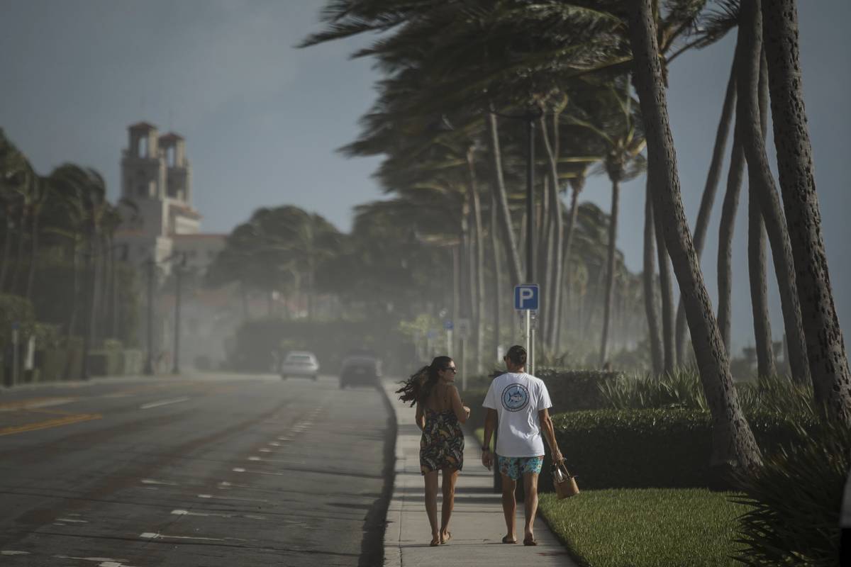 Sea spray, sand and winds sweep across South Ocean Boulevard in Palm Beach, Fla., as Palm Beach ...