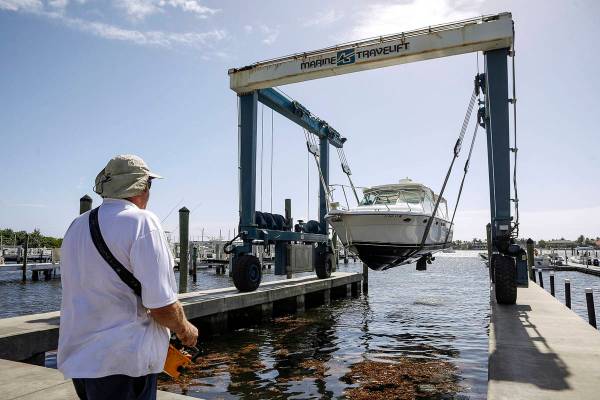 Brett Hand controls a Marine Travelift with a hand held remote to lift boats out of the water a ...