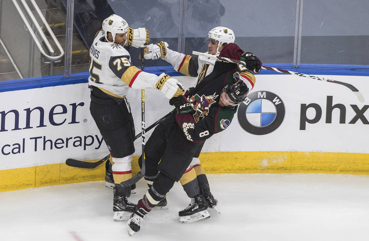 Arizona Coyotes' Nick Schmaltz (8) is checked by Vegas Golden Knights' Ryan Reaves (75) and Zac ...