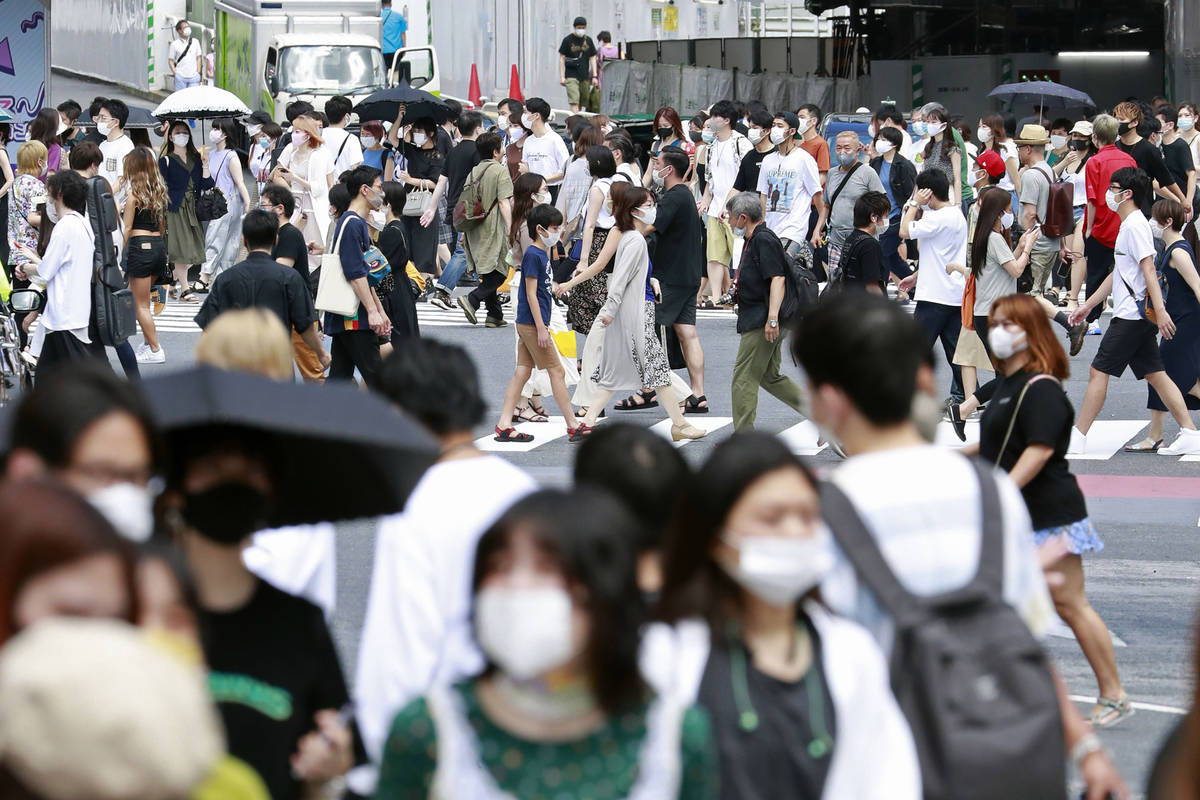 People cross the streets in Tokyo Sunday, Aug. 2, 2020. Confirmed coronavirus cases are hoverin ...