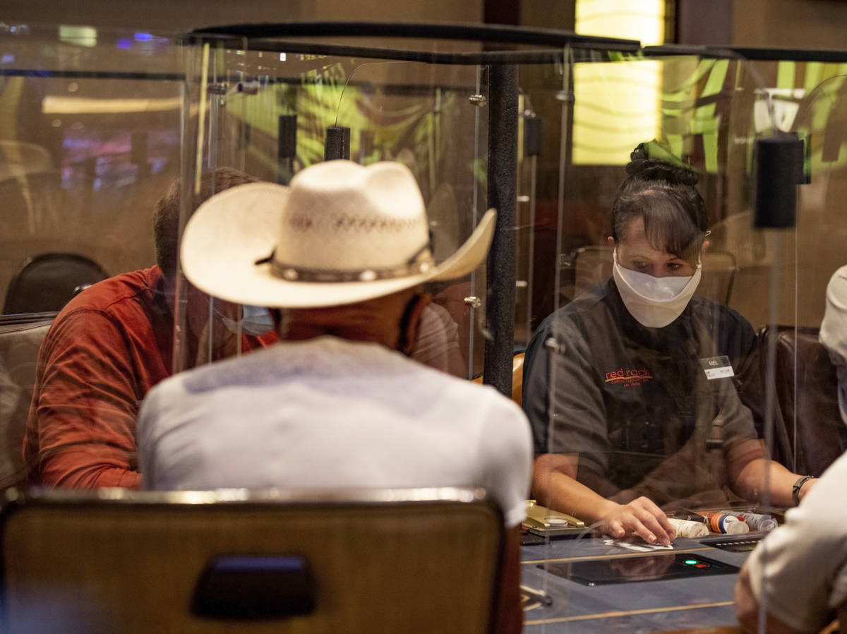 Poker dealer Melissa Moses deals an eight-handed game protected by plexiglass dividers, at the ...