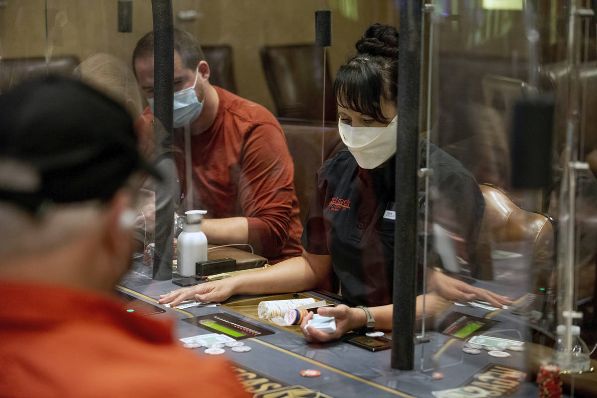 Poker dealer Melissa Moses deals an eight-handed game protected by plexiglass dividers, at the ...