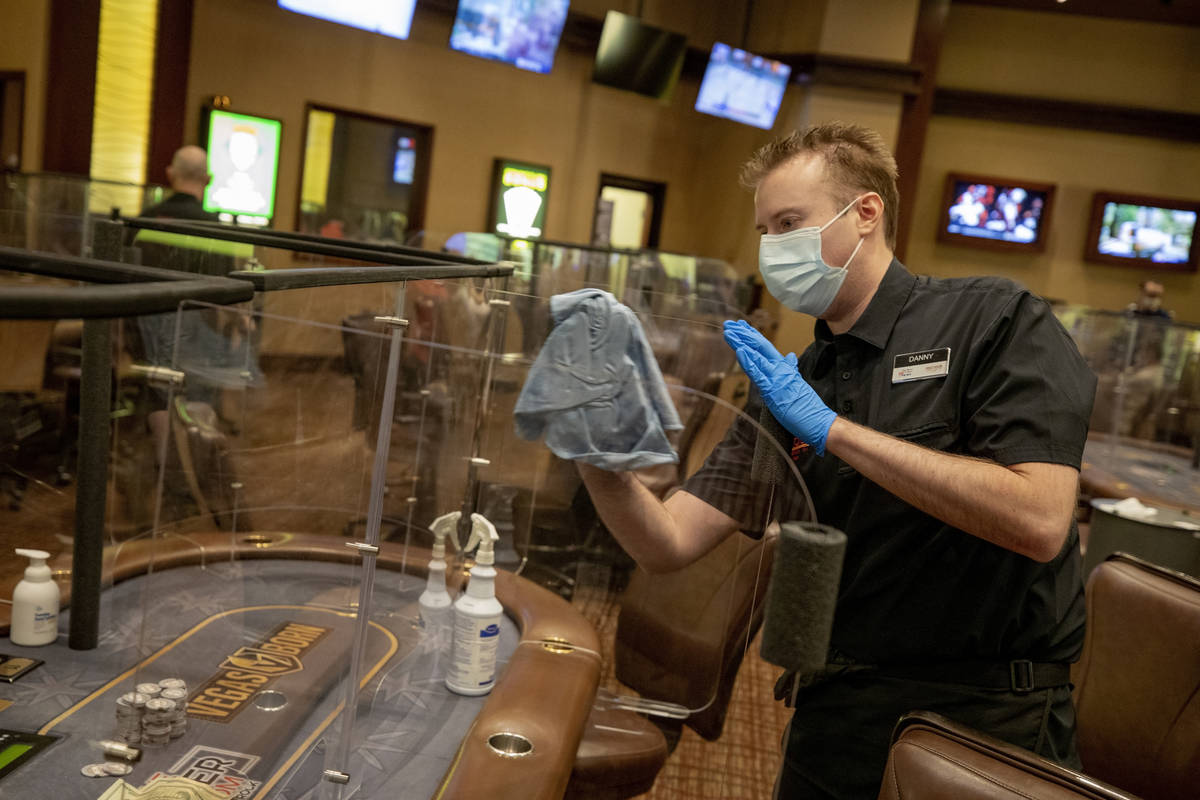 Poker dealer Daniel Wilson sanitizes plexiglass dividers, at the Red Rock Resort poker room in ...