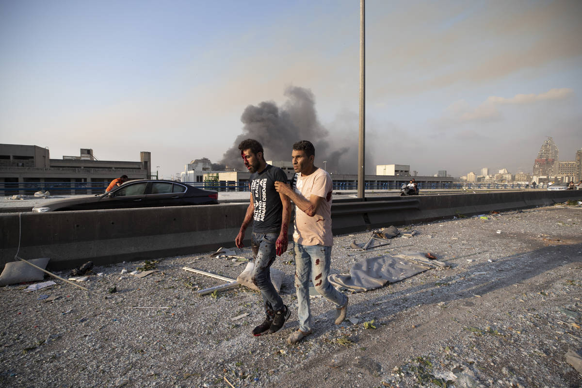 A man wounded in a massive explosion is led away in Beirut, Lebanon, Tuesday, Aug. 4, 2020. Mas ...