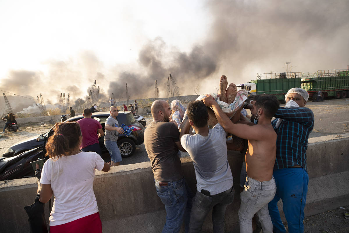 People evacuate wounded after of a massive explosion in Beirut, Lebanon, Tuesday, Aug. 4, 2020. ...
