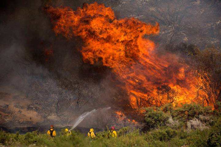 Firefighters work against the Apple Fire near Banning, Calif., on Sunday, Aug. 2, 2020. Smoke f ...