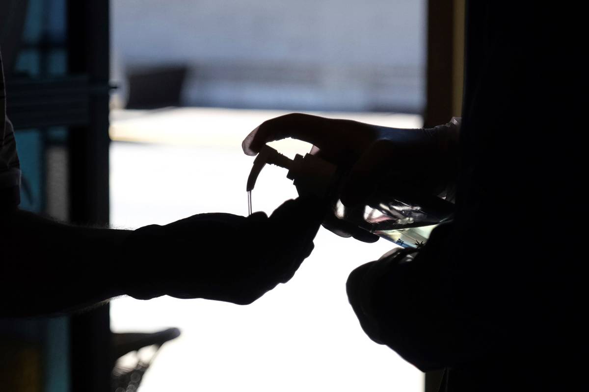 Hand sanitizer is squirted into a worshiper's hands as they enter for a Sunday Mass at a church ...