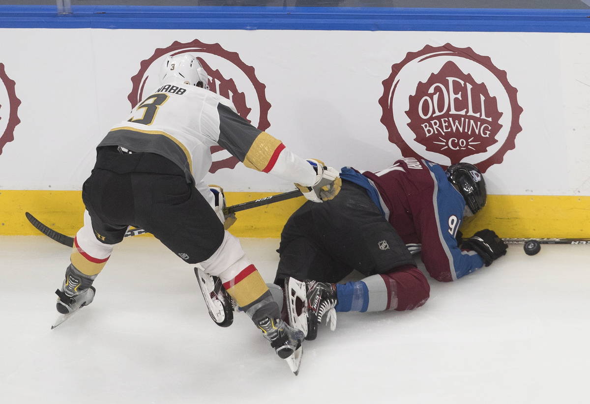 Colorado Avalanche's Nazem Kadri (91) is checked into the boards by Vegas Golden Knights' Brayd ...