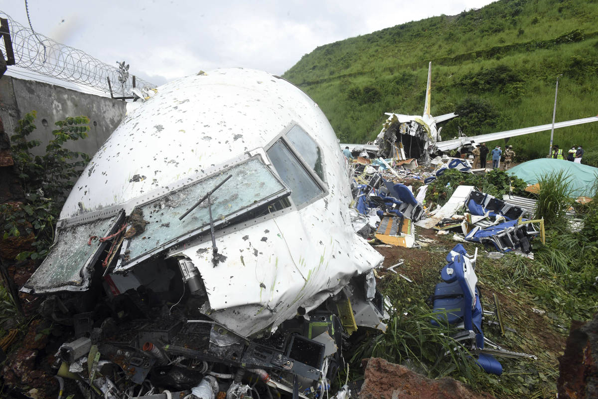 People stand by the debris of the Air India Express flight that skidded off a runway while land ...