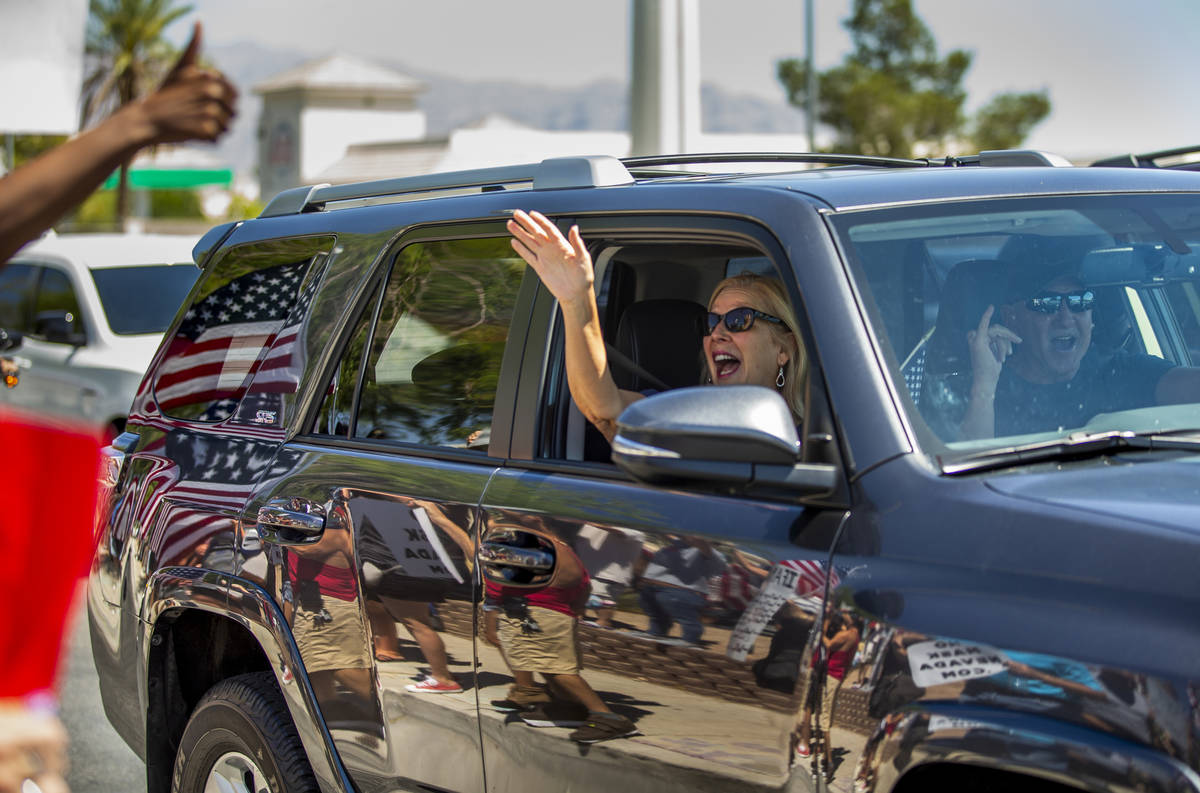 A driver and passenger show their support as they pass by a No Mask Nevada rally to oppose the ...