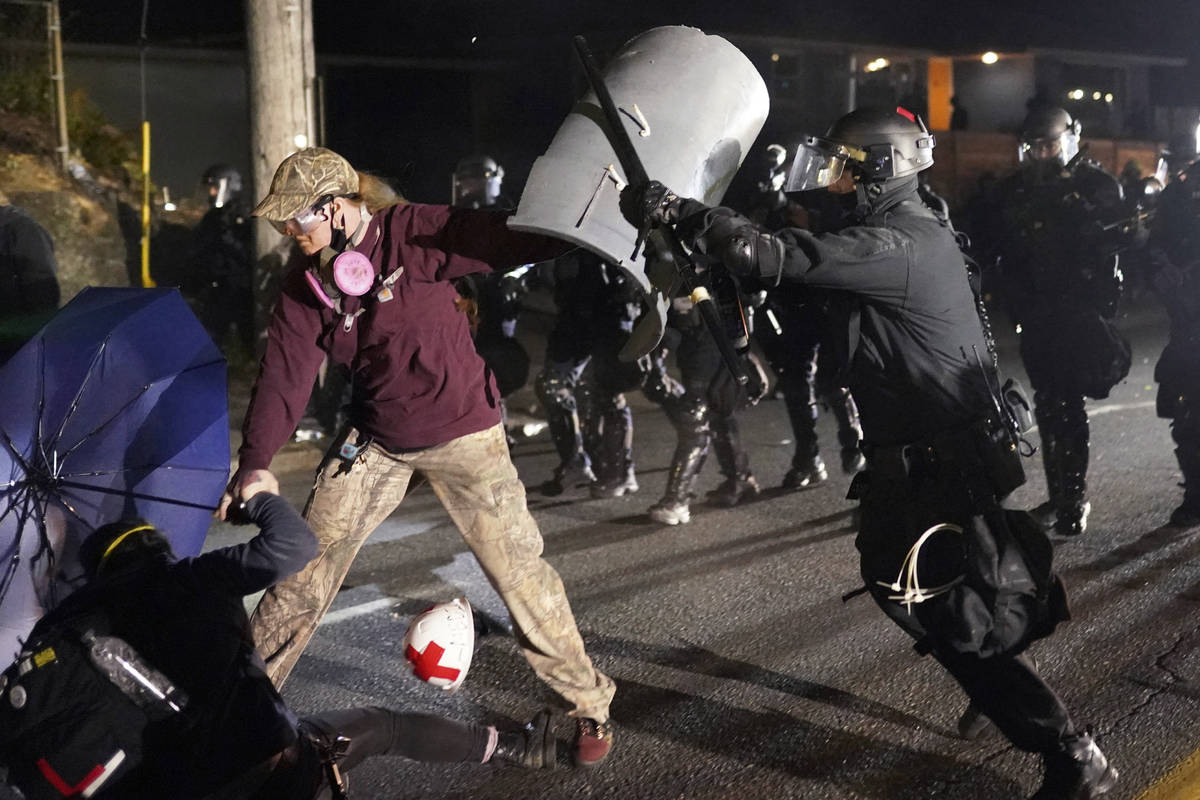 A Portland police officer shoves a protester as police try to disperse the crowd in front of th ...