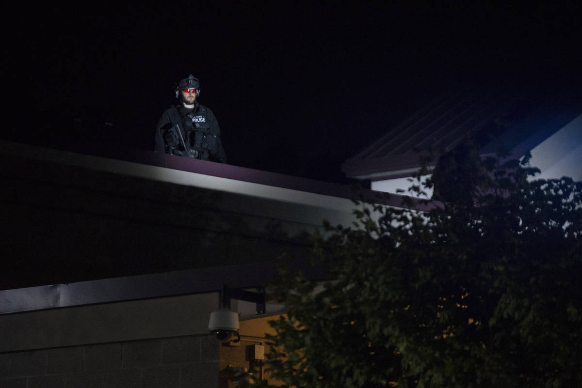 CORRECTS DAY TO FRIDAY - A Portland police officer watches from the roof of the Multnomah Count ...