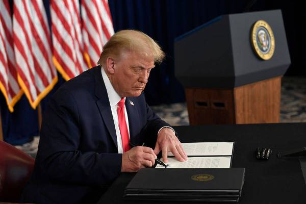 President Donald Trump signs one of four executive orders addressing the economic fallout from ...