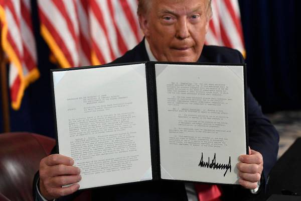 President Donald Trump hold up one of the four executive orders that he signed that addresses t ...