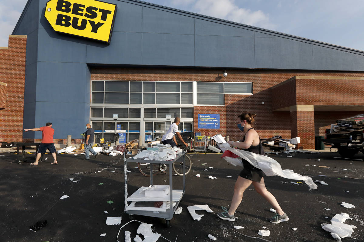 Volunteers help clean up the parking lot outside a Best Buy store, Monday, Aug. 10, 2020, after ...