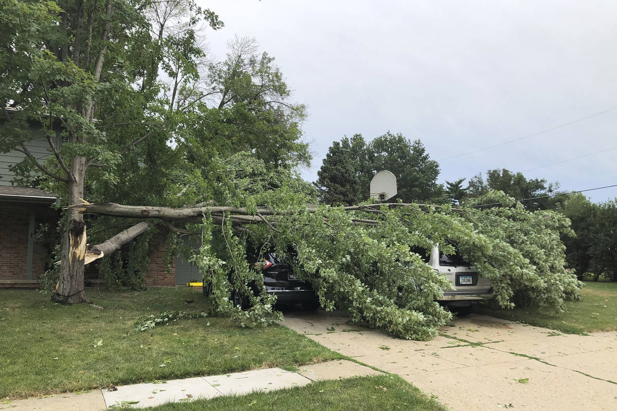 A tree fell across vehicles at a home in West Des Moines, Iowa, after a severe thunderstorm mov ...