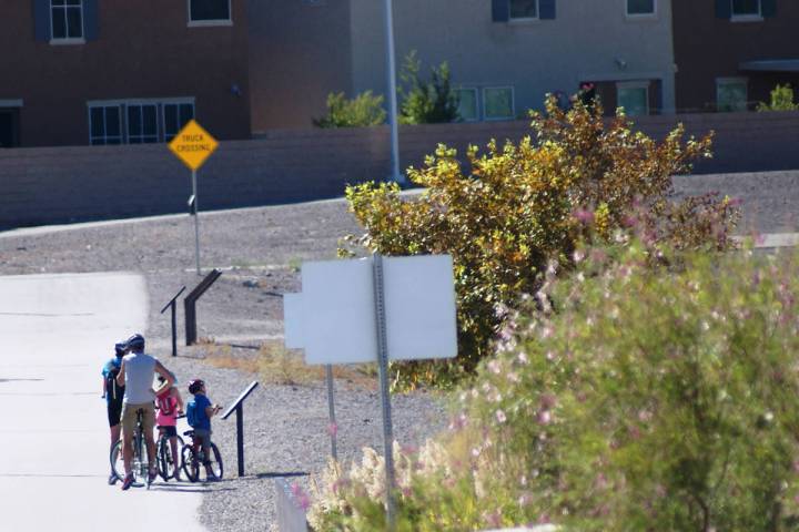 A family biking at Cornerstone Park stops in late July to read a "Story Walk" panel from the hu ...