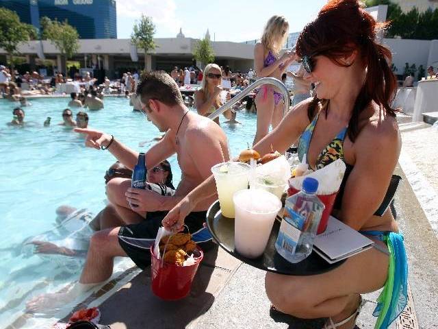 A cocktail server brings drinks and food to customers at the Wet Republic adult pool and beach ...