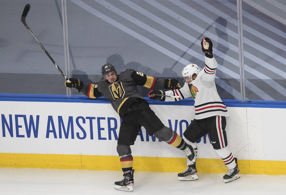 Vegas Golden Knights' Alec Martinez (23) is checked by Chicago Blackhawks' Drake Caggiula (91) ...