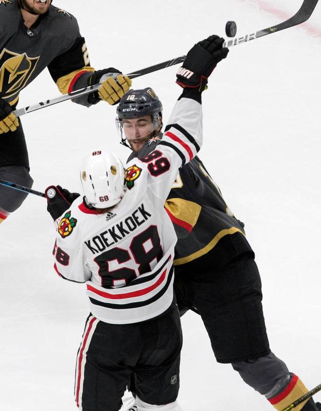 Vegas Golden Knights' Nicolas Roy (10) and Chicago Blackhawks' Slater Koekkoek (68) reach for t ...