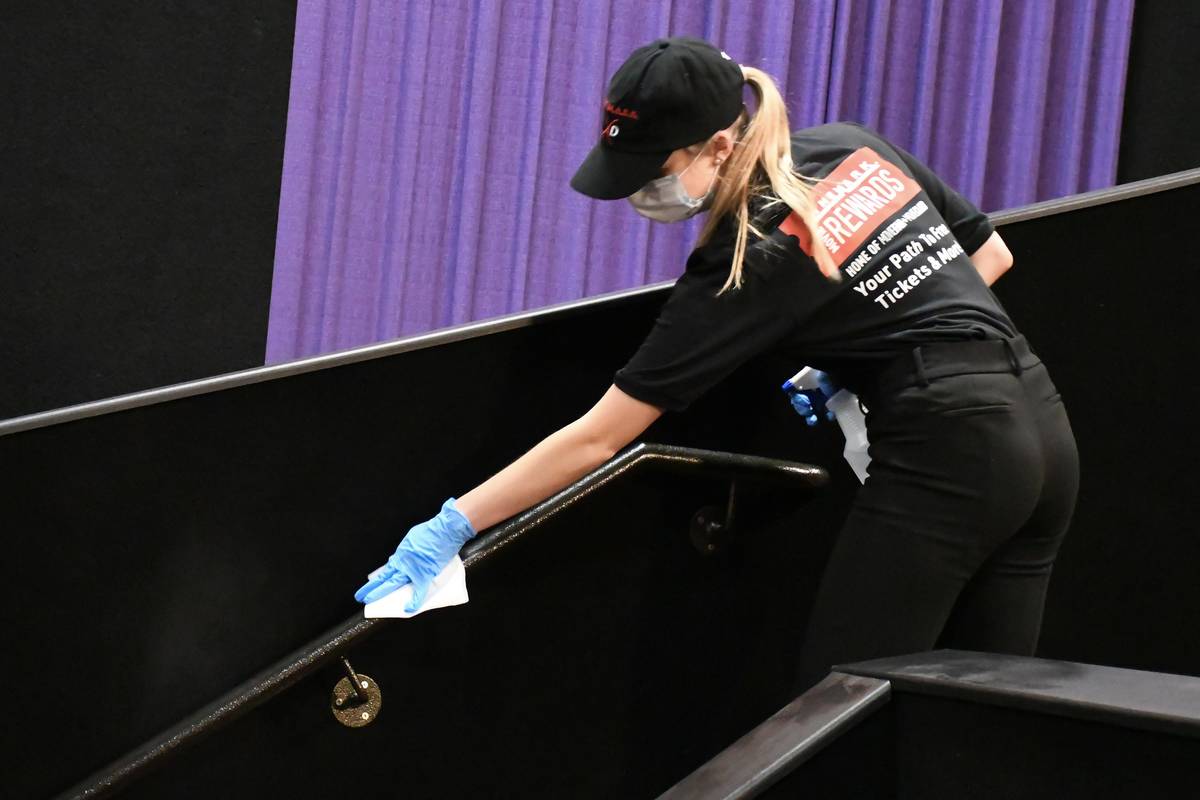 A Cinemark employee cleans inside an auditorium. Five Century-branded movie theaters operated b ...