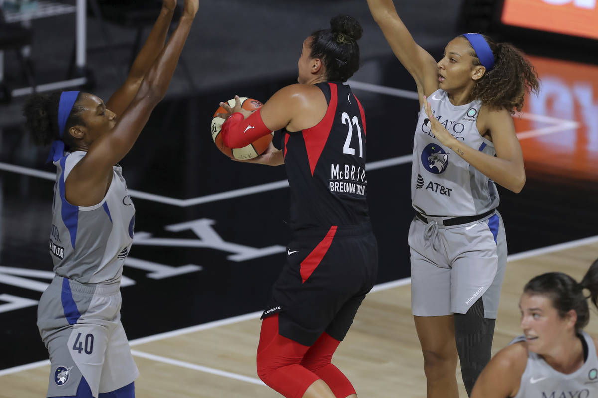 Las Vegas Aces' Kayla McBride (21) drives between Minnesota Lynx's Kayla Alexander (40) and Mik ...