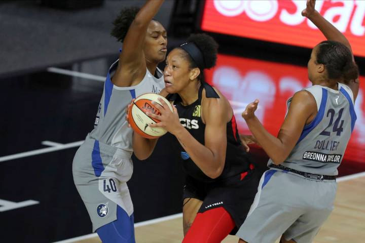 Las Vegas Aces' A'ja Wilson drives between Minnesota Lynx's Kayla Alexander (40) and Napheesa C ...