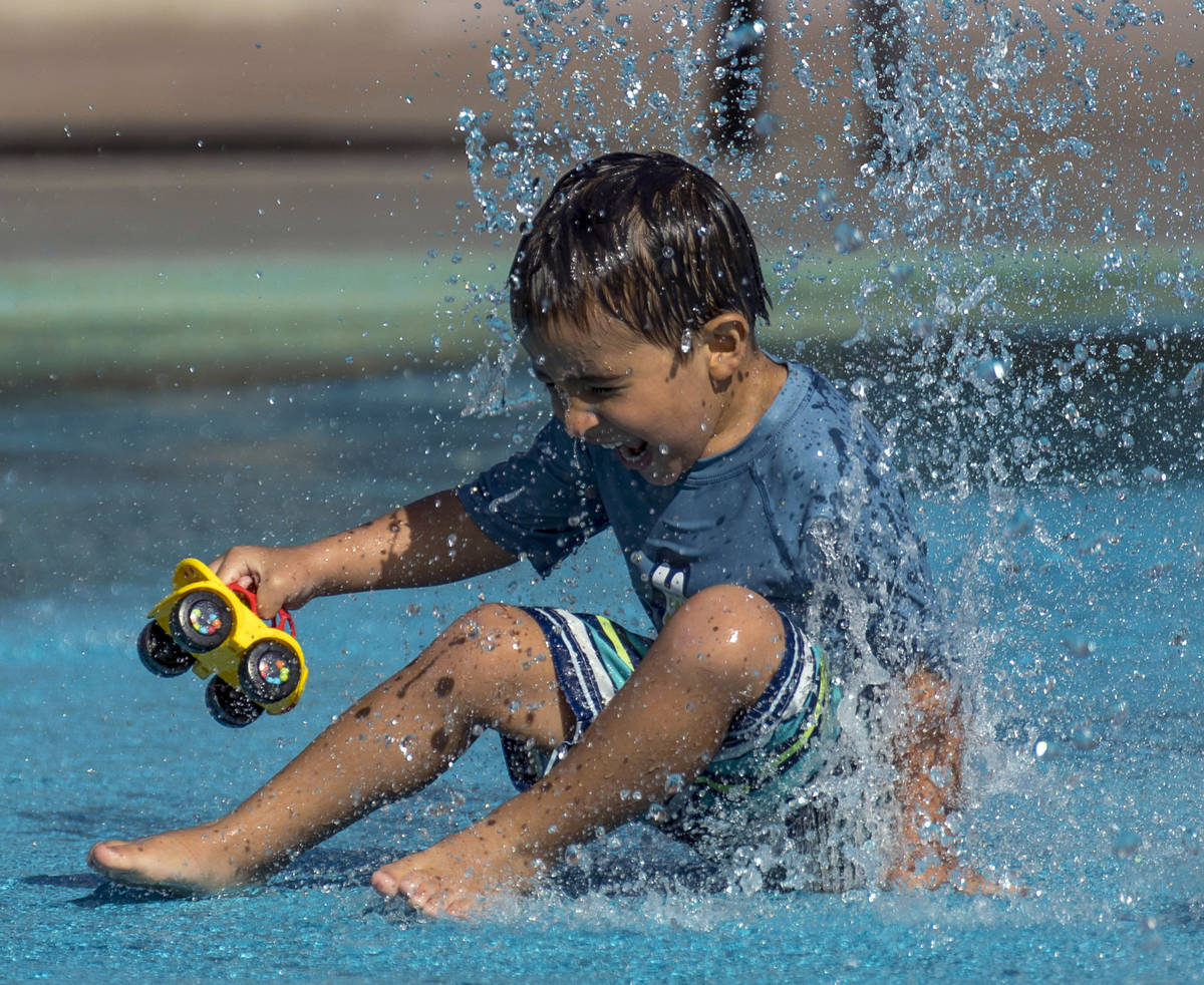 Leo Reyes, 3, sits on a water fountain as he stays cool on the splash pad at The Paseos Park on ...