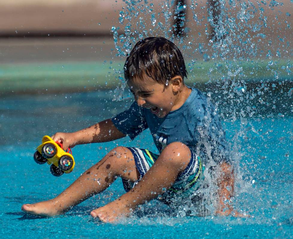 Leo Reyes, 3, sits on a water fountain as he stays cool on the splash pad at The Paseos Park on ...